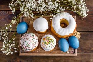 Festive cakes with white glaze, nuts and raisins with Easter eggs on the festive table photo