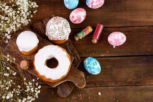 Festive cakes with white glaze, nuts and raisins with Easter eggs on the festive table photo