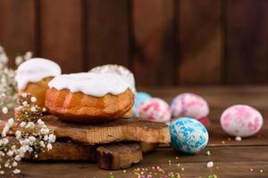 Pasteles festivos con glaseado blanco, nueces y pasas con huevos de pascua en la mesa festiva