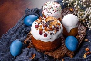 Festive cakes with white glaze, nuts and raisins with Easter eggs on the festive table photo