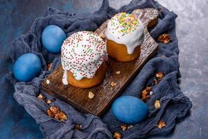 Festive cakes with white glaze, nuts and raisins with Easter eggs on the festive table photo