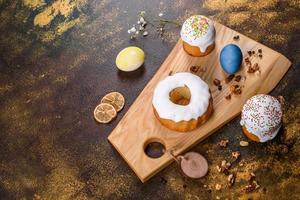 Festive cakes with white glaze, nuts and raisins with Easter eggs on the festive table photo