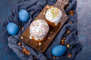 Festive cakes with white glaze, nuts and raisins with Easter eggs on the festive table photo