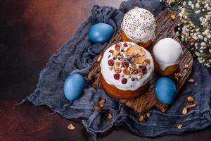 Festive cakes with white glaze, nuts and raisins with Easter eggs on the festive table photo