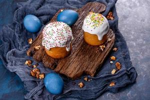 Festive cakes with white glaze, nuts and raisins with Easter eggs on the festive table photo