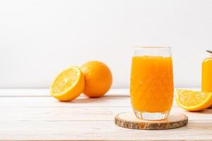 Vaso de jugo de naranja fresco sobre fondo de madera foto