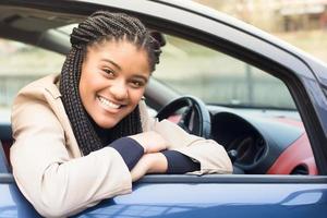 Feliz mujer afroamericana en un automóvil, otoño-invierno foto