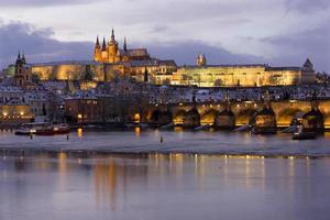 Noche de Navidad nevada colorida ciudad menor de Praga con el castillo gótico y el puente de Carlos, República Checa