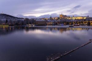 Noche de Navidad nevada colorida ciudad menor de Praga con el castillo gótico y el puente de Carlos, República Checa foto