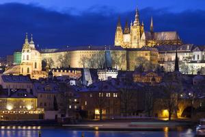Noche de Navidad nevada colorida ciudad menor de Praga con el castillo gótico y el puente de Carlos, República Checa