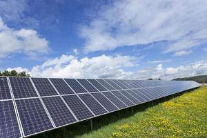 Estación de energía solar en la pradera de flores de primavera foto