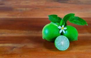 Flower, cut and whole limes on wooden background photo