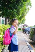 Niña con mochila caminando en el aparcamiento listo para volver a la escuela foto