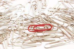 Red paper clip show different from the others on white background photo