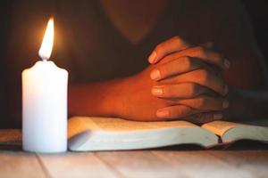 Conceptos religiosos, el joven oró sobre la Biblia en la habitación y encendió las velas para iluminar. foto