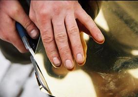 Photo depicts a man cuts the yellow metal scissors