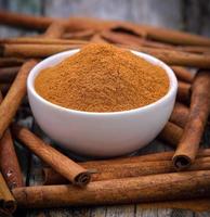 Palitos de canela y canela en polvo en el recipiente sobre la mesa foto