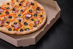 Fresh delicious pizza made in a hearth oven with olives, chili pepper and ham photo