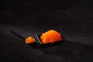 Delicioso caviar rojo fresco sobre una mesa de hormigón oscuro