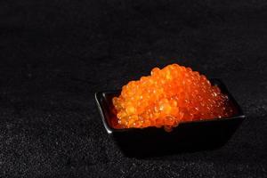 Delicioso caviar rojo fresco sobre una mesa de hormigón oscuro