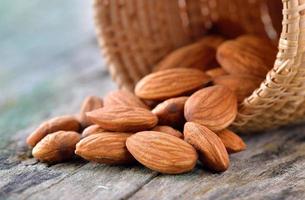 Almendras en la canasta sobre fondo de madera vieja foto