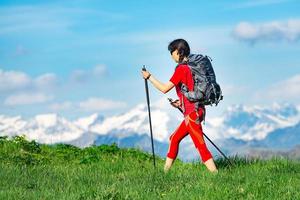 Chica vestida de rojo con mochila practica trekking foto