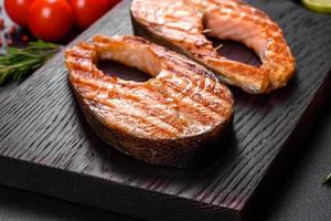 Fresh cooked delicious salmon steak with spices and herbs baked on a grill photo