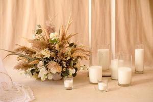 Decoraciones de hermosas flores secas en un jarrón blanco sobre un fondo de tela beige foto