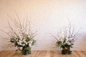 Decoraciones de ramas con hermosas flores rosas y blancas en la canasta con el telón de fondo de una pared de ladrillo blanco. foto