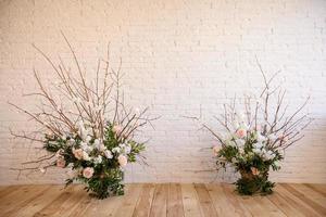 Decoraciones de ramas con hermosas flores rosas y blancas en la canasta con el telón de fondo de una pared de ladrillo blanco. foto