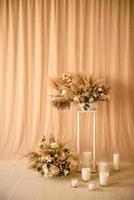 Decoraciones de hermosas flores secas en un jarrón blanco sobre un fondo de tela beige foto