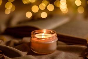 una vela encendida en una mesa de madera frente a un libro a media asta foto