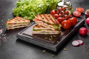 delicioso sándwich con tostadas crujientes, jamón, lechuga y tomates foto