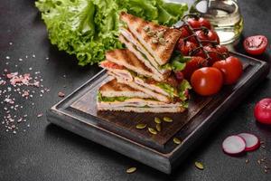 Delicious sandwich with crisp toast, ham, lettuce and tomatoes photo