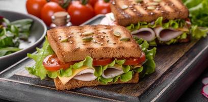 delicioso sándwich con tostadas crujientes, jamón, lechuga y tomates foto