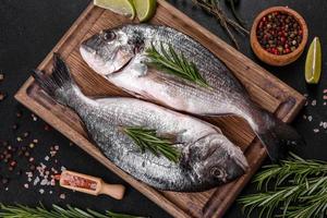 Pescado dorado crudo con especias para cocinar en la tabla de cortar. dorado de pescado fresco foto