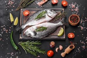 Pescado dorado crudo con especias para cocinar en la tabla de cortar. dorado de pescado fresco foto