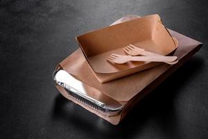 Disposable dishes made of environmentally friendly brown cardboard on a dark background photo