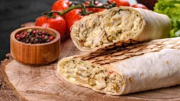 Delicious fresh shawarma with meat and vegetables on a dark concrete table photo