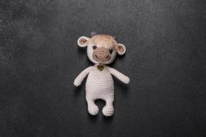 Knitted toy bull of light threads on a dark background photo