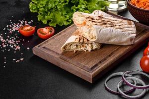 Delicious fresh shawarma with meat and vegetables on a dark concrete table photo