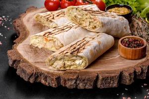 Delicious fresh shawarma with meat and vegetables on a dark concrete table photo