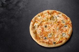 Sabrosa pizza fresca al horno con tomates, queso y champiñones sobre un fondo de hormigón oscuro