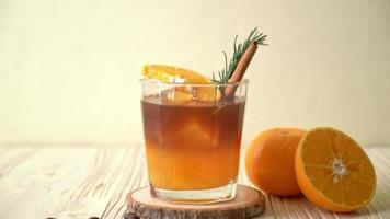 A glass of iced americano black coffee and layer of orange and lemon juice decorated with rosemary and cinnamon video