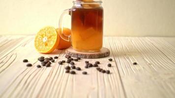 un verre de café noir americano glacé et une couche de jus d'orange et de citron décoré de romarin et de cannelle