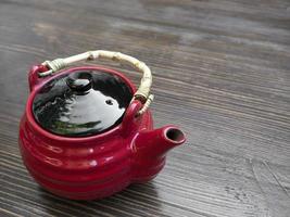Red Chinese teapot on a wooden table photo