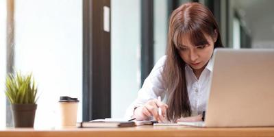 Portrait of a pretty young woman studying while sitting at the table photo