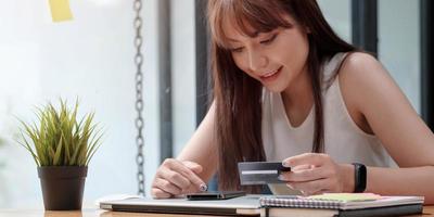 Mujer sonriente utilice el teléfono móvil para comprar en línea con tarjeta de crédito foto