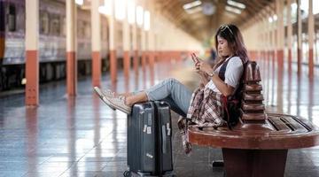 Mujer joven con su teléfono inteligente mientras espera el tren foto
