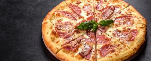 Delicious fresh crispy pizza from the oven with ham, cheese and basil photo